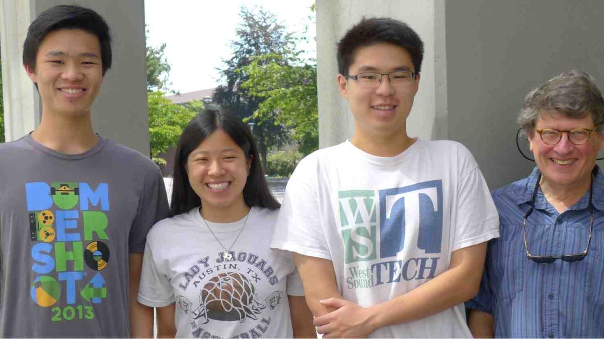 Dr. Monnat stands next to three former undergraduate lab assistants