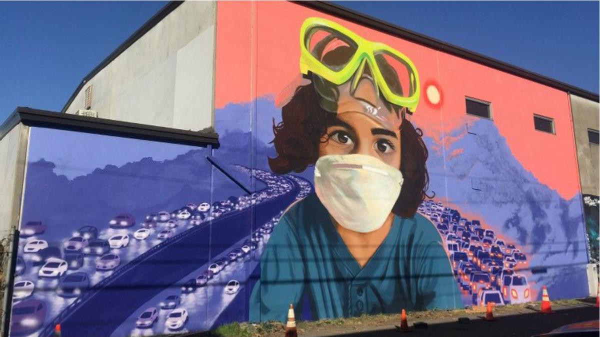 Mural art showing child wearing mask with traffic in background