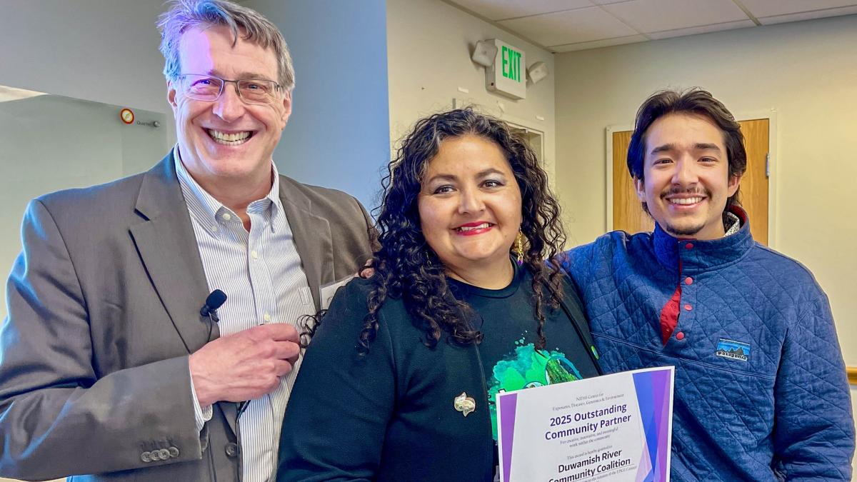 Three people pose with a certificate. 
