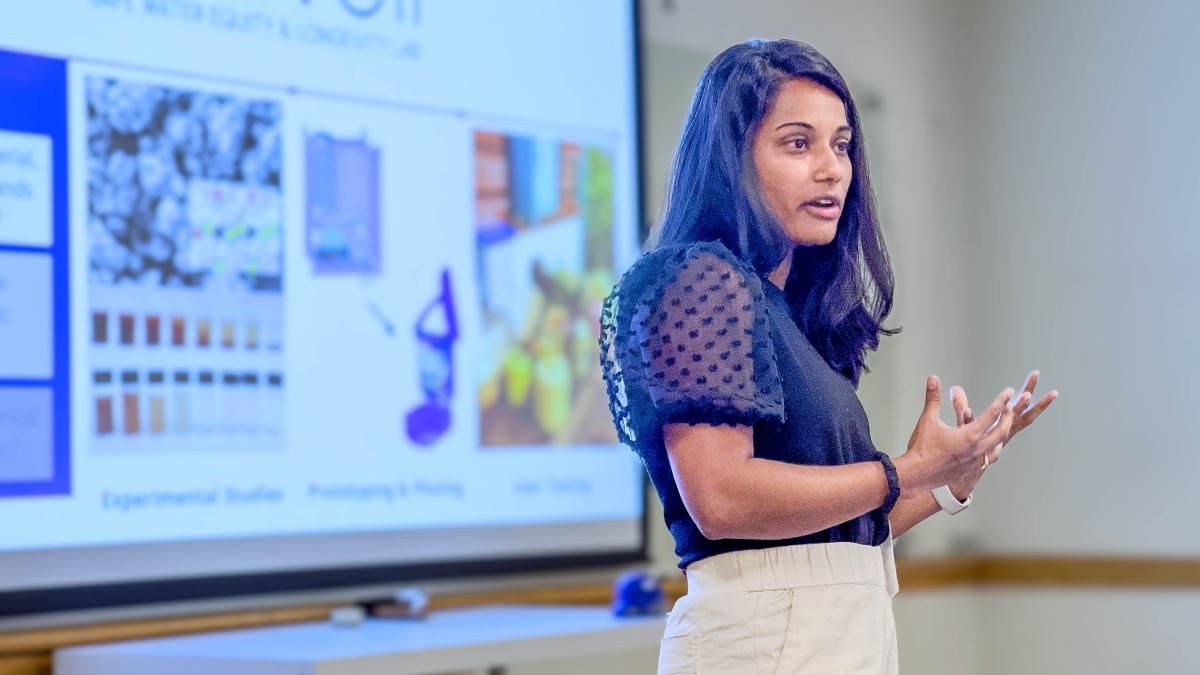 A woman presents in front of a slide. 