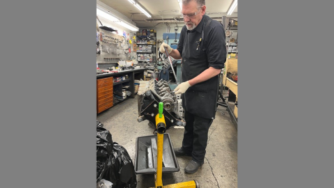 A worker in a mechanics shop handles machinery