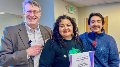 Three people pose with a certificate. 