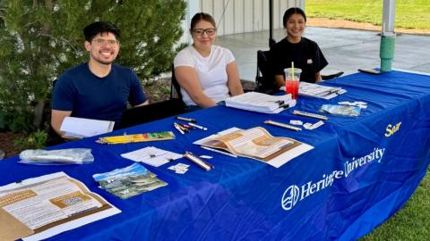 Three researchers sit at a table to recruit study participants