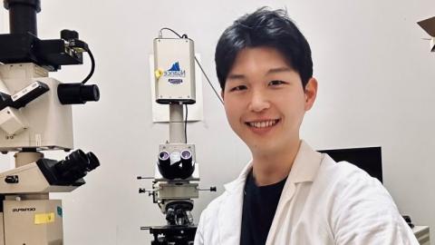 Head shot of Joe Lim wearing a white coat in a lab. 