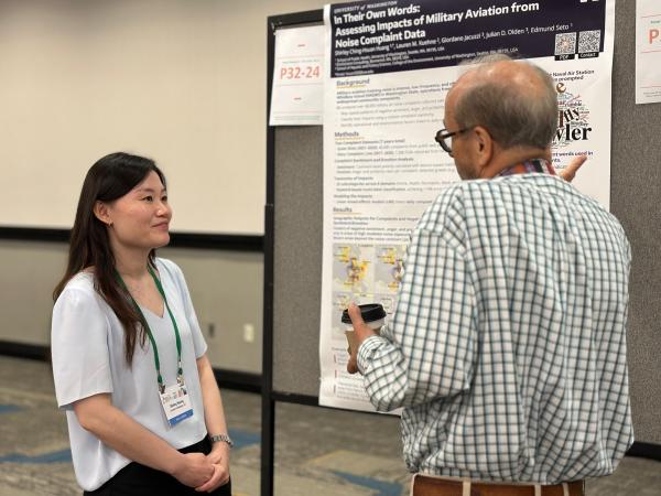 A researcher talks with a conference attendee in front of her poster