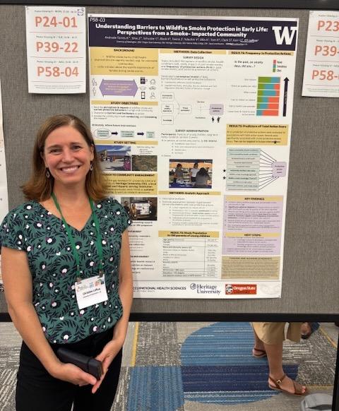 A researcher poses by her research poster
