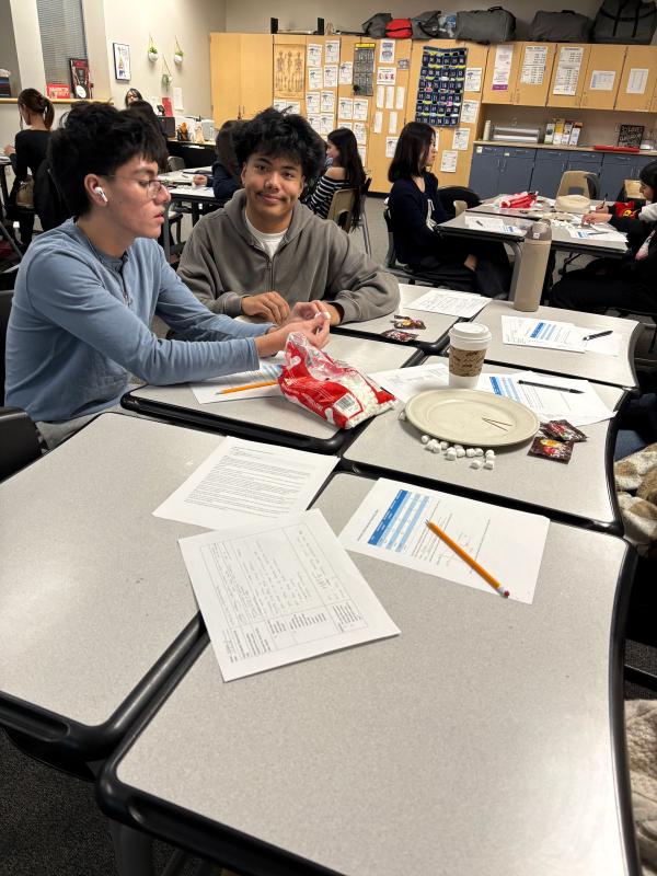 Two high school students take marshmallows from a bag. 