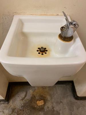A dated and discolored porcelain drinking fountain